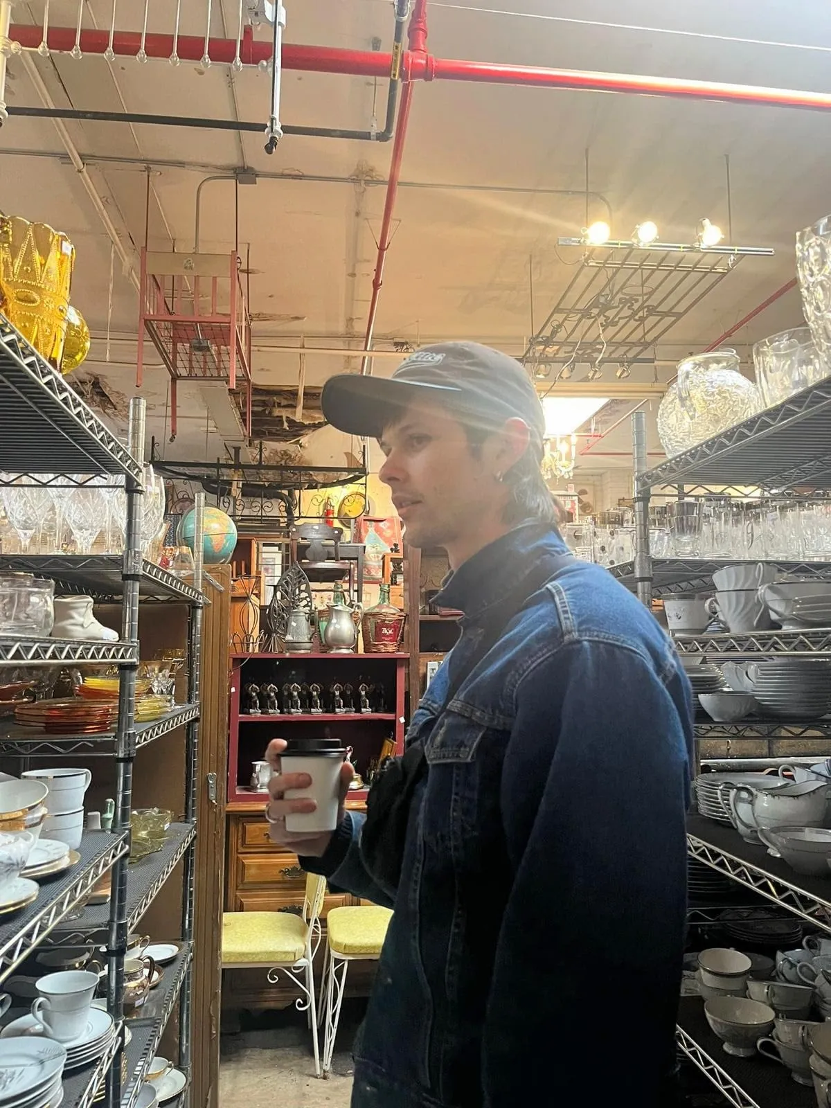 Josh in a cap and denim jacket in a cookware shop