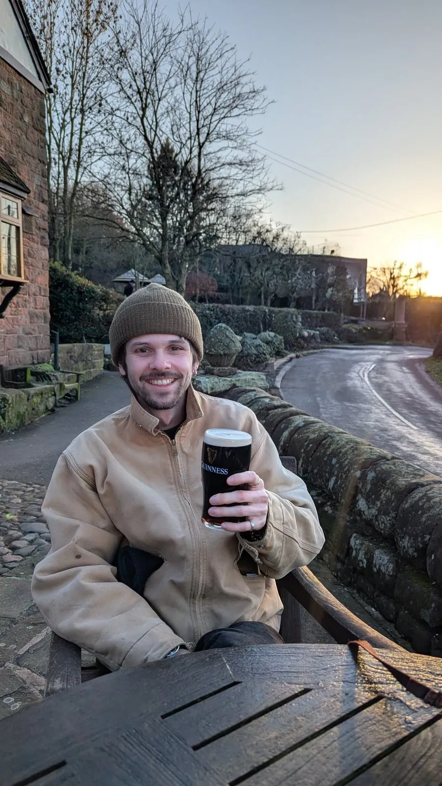 Josh smiling with a pint of Guinness on a country lane